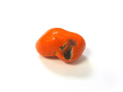 Orange double nut, with a sizeable uncoated patch and a crack, sprawling on the floor.