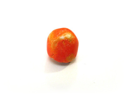 A grainy, faded orange nut, somewhat faceted.