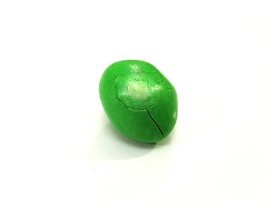 A mid-sized green nut, with a centered pale impact spot, a round crack surrounding it, and some radial fractures.